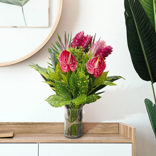 Tropical Bouquet on table with (1) Ginger Pink, (3) Ginger Red, (2) Anthurios, (2) Hel. Sassy, (2) Eucaliptos doll, (3) Lettuce Fern, (2) Palma Flecha, (2) Diafembancha, (2) Croto Pecoso, (1) Tip Bronce, (6) Codelines. 